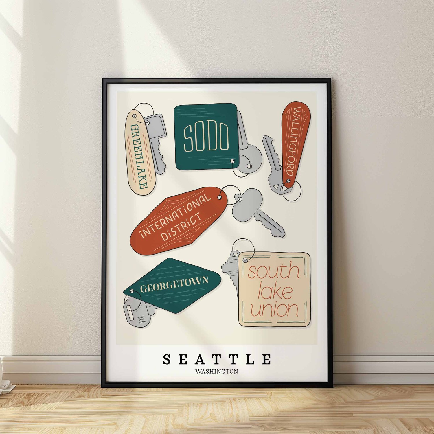 A framed picture of Seattle neighborhoods drawn in various lettering styles on key fobs. Artwork has a orange, green and beige color scheme