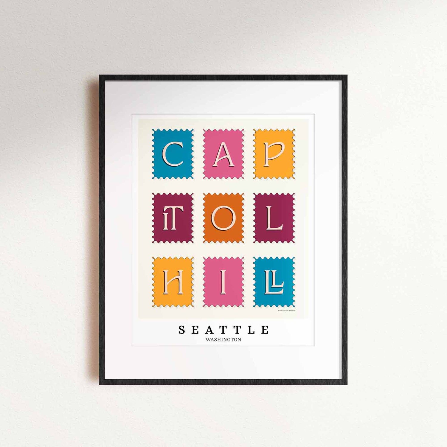 A framed picture of postage stamps featuring the Capitol Hill neighborhood in Seattle, Washington drawn in a unique lettering style. Artwork has a bright blue, orange and purple color scheme