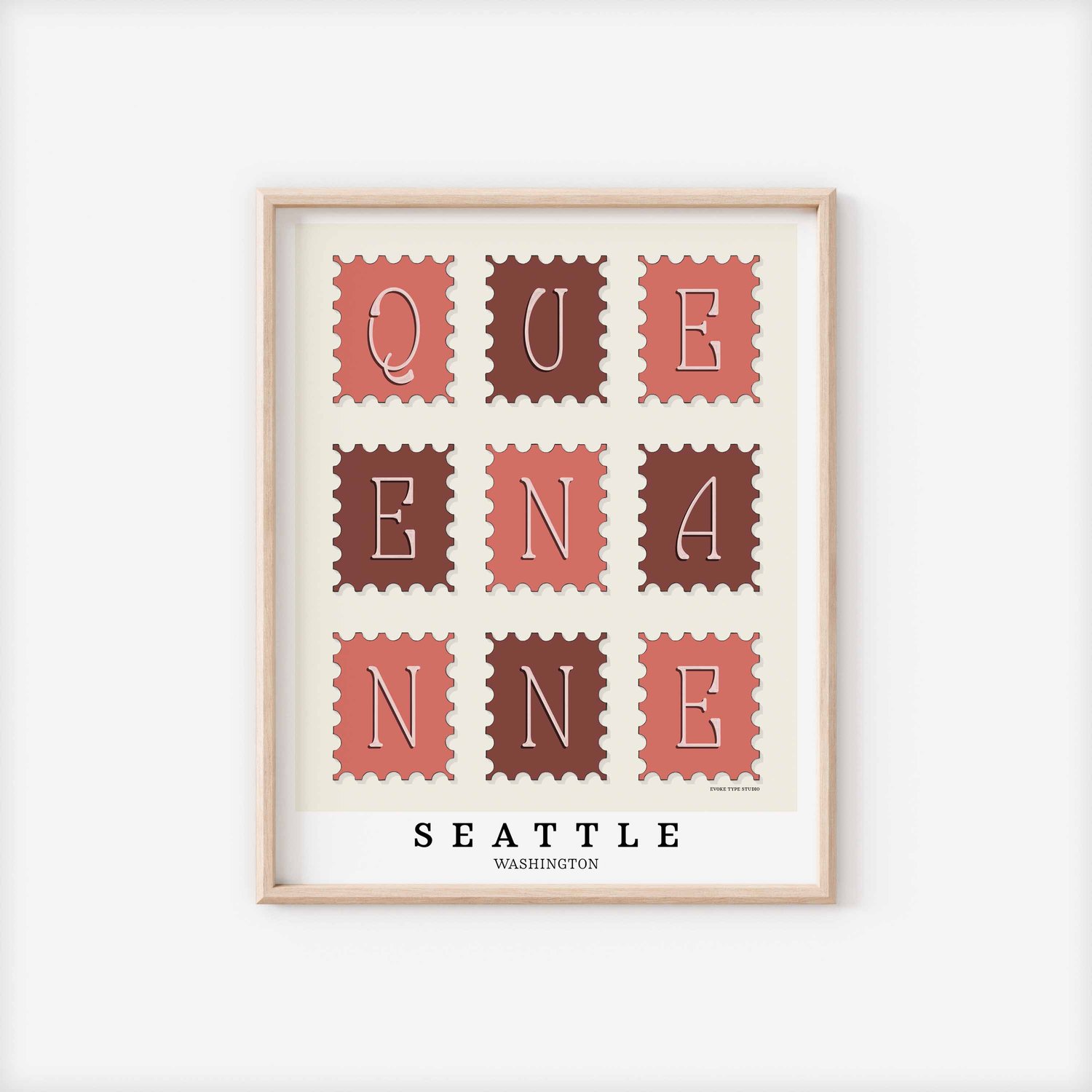 A framed picture of postage stamps featuring the Queen Anne neighborhood in Seattle, Washington drawn in a unique lettering style. Artwork has a pink, burgundy and white color scheme