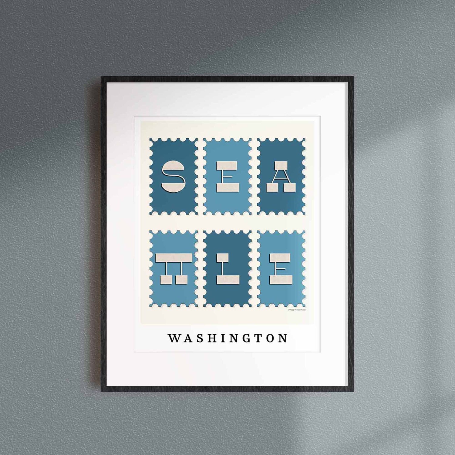 A framed picture of postage stamps featuring Seattle, Washington drawn in a unique lettering style. Artwork has a blue and beige color scheme