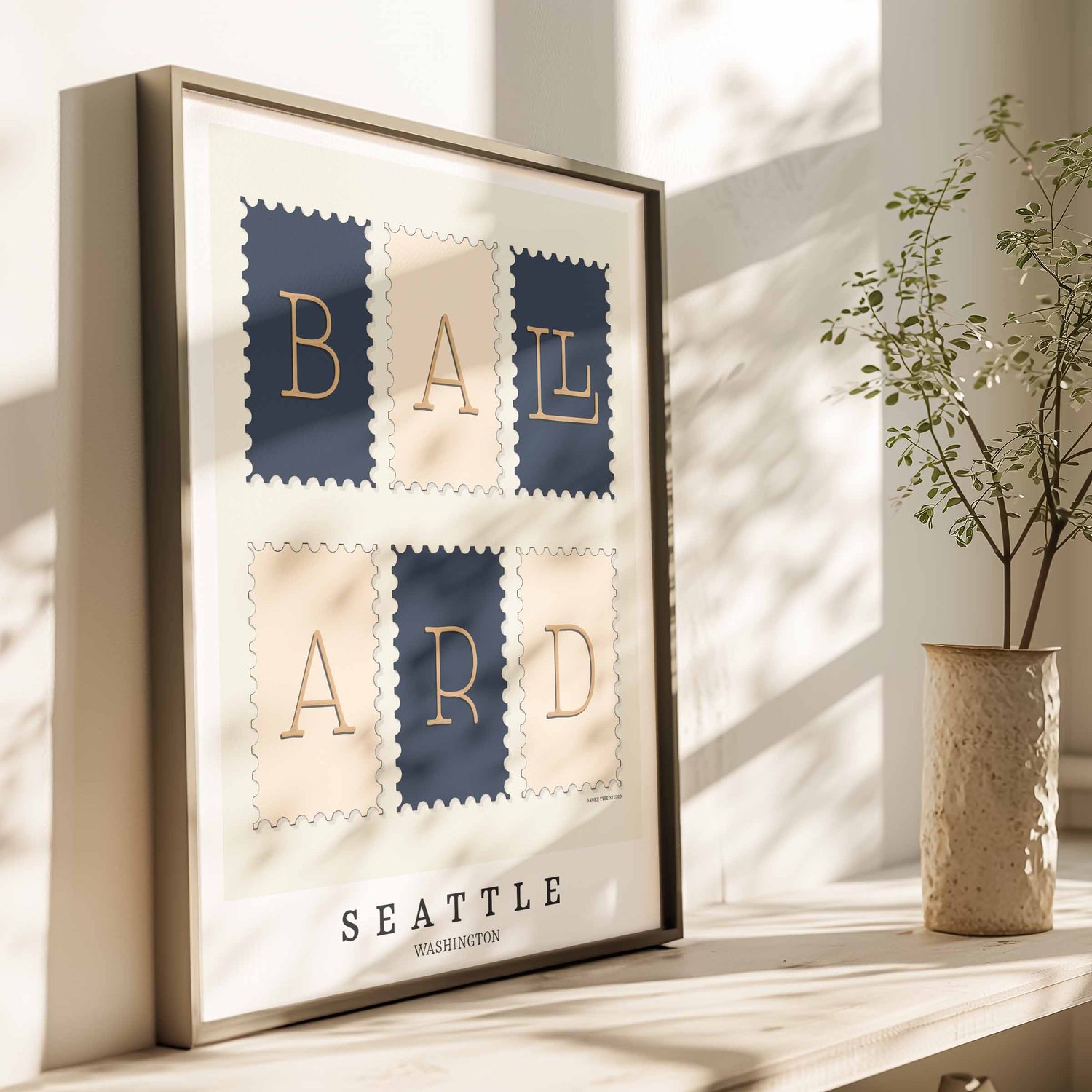 A framed picture of postage stamps featuring the Ballard neighborhood in Seattle, Washington drawn in a unique lettering style. Artwork has a navy blue, tan and beige color scheme