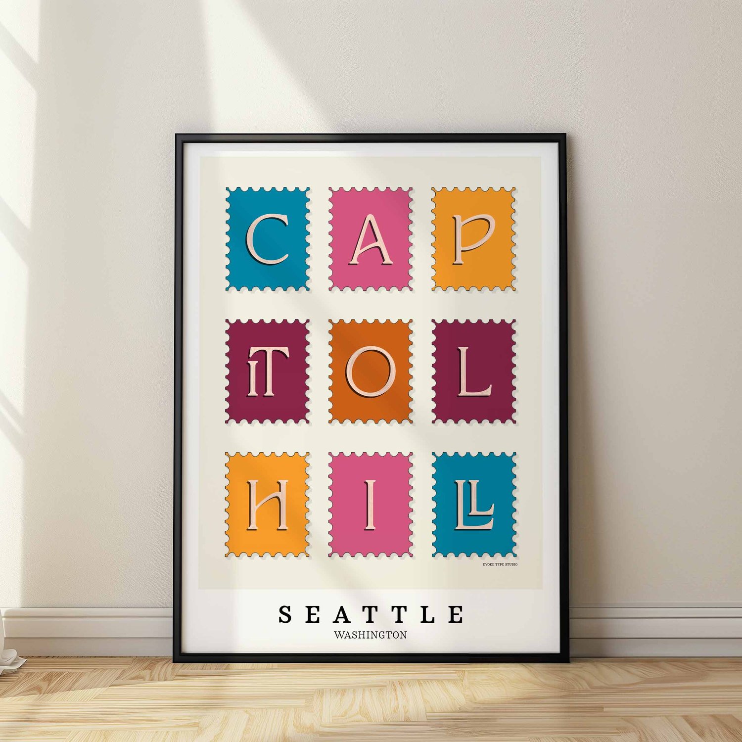 A framed picture of postage stamps featuring the Capitol Hill neighborhood in Seattle, Washington drawn in a unique lettering style. Artwork has a bright blue, orange and purple color scheme