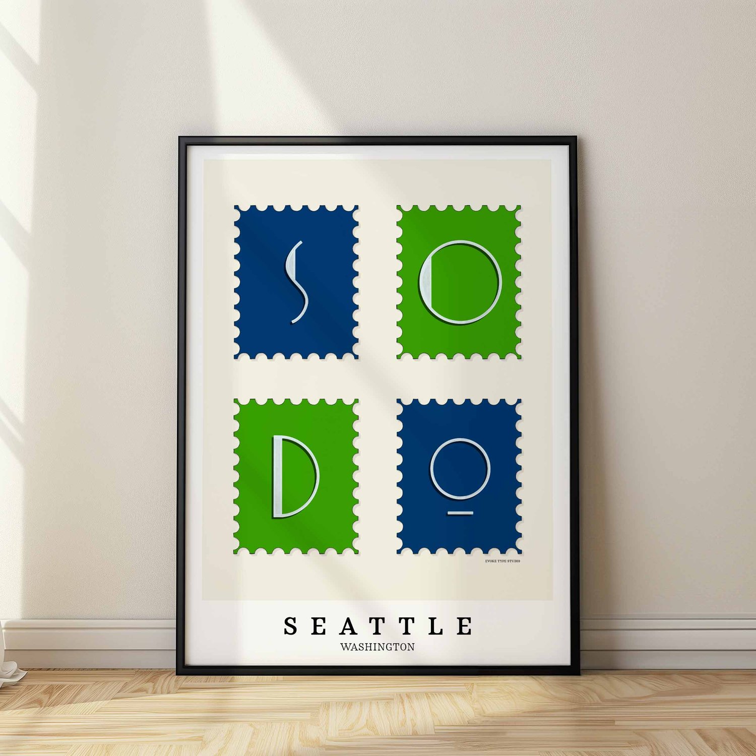 A framed picture of postage stamps featuring the SoDo neighborhood in Seattle, Washington drawn in a unique lettering style. Artwork has a bright blue and green color scheme