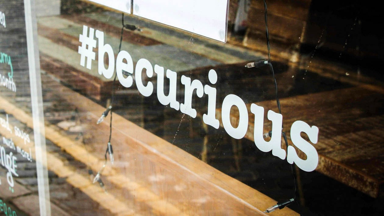 Window signage reading “#becurious” photographed by Gary Butterfield, representing the concept of radical curiosity in creative thinking from The Creative Guide.