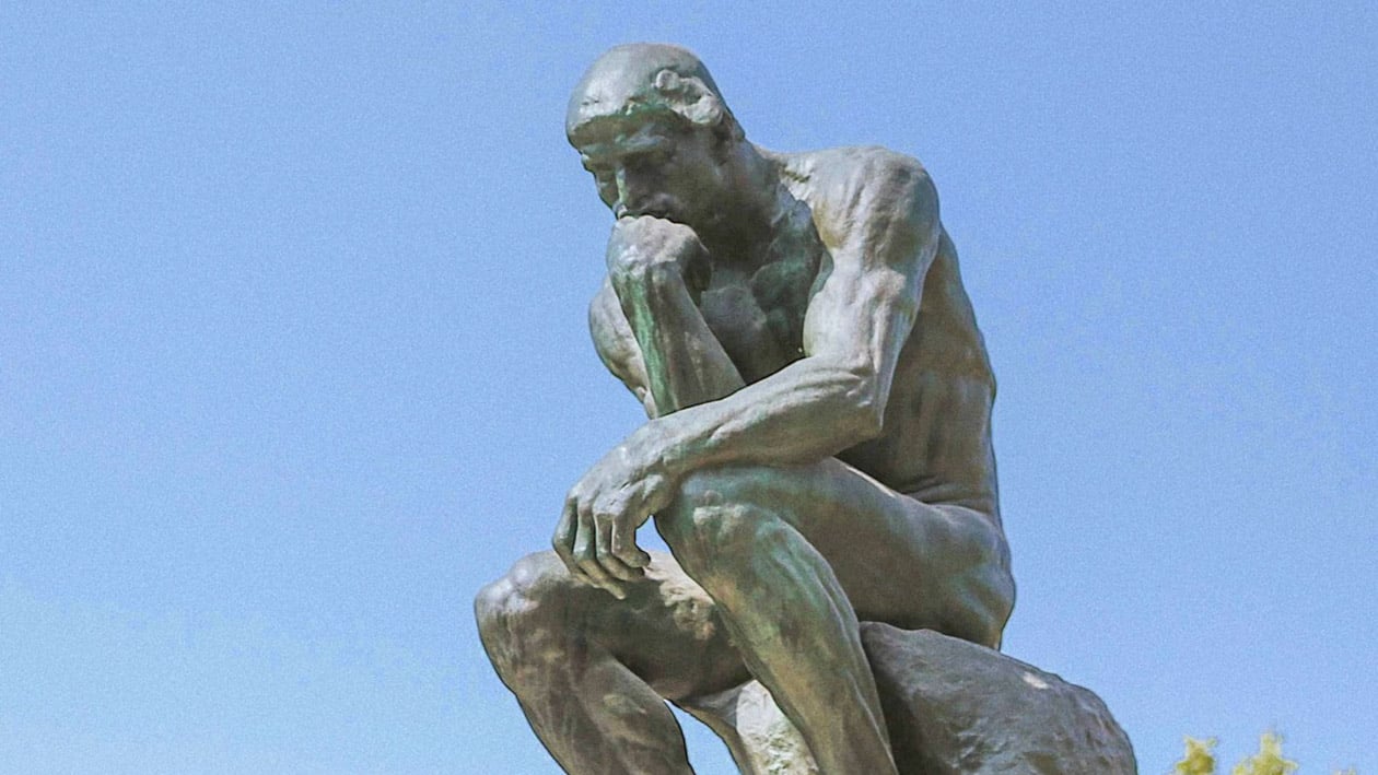 Auguste Rodin’s bronze sculpture “The Thinker” under a clear blue sky, representing the reflective mindset and preparation required to succeed in an online photography course, featured in The Creative Guide blog post “How to Get the Best Out of Any Online