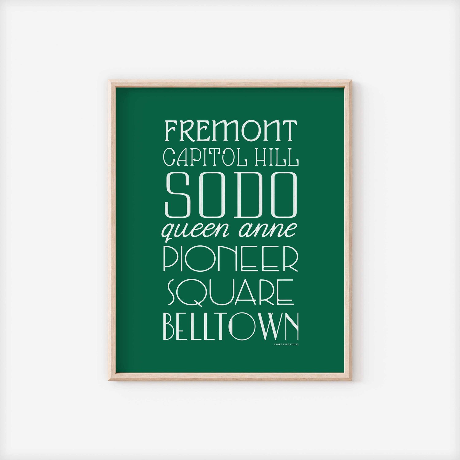 A framed picture of Seattle, Washington neighborhoods drawn in various lettering styles. Artwork has a green and white color scheme