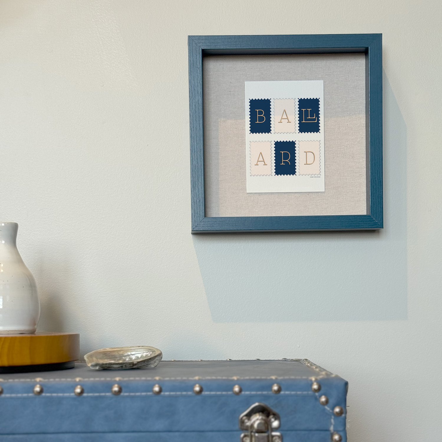 A framed notecard in a shadow box hung on the wall with decorative items placed nearby.