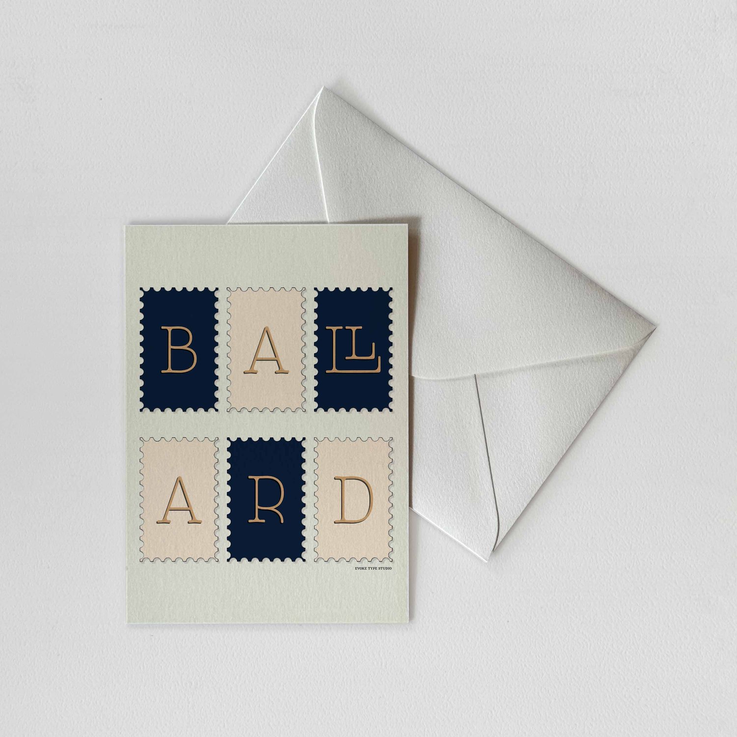 A notecard of postage stamps featuring the Ballard neighborhood in Seattle, Washington drawn in a unique lettering style with a white envelope. Artwork has a navy blue, beige and tan color scheme
