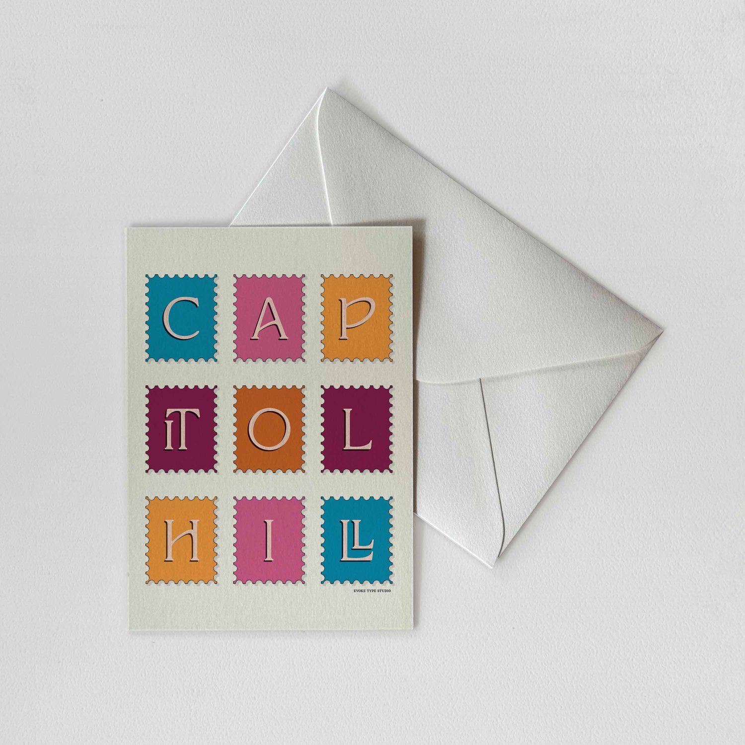 A notecard of postage stamps featuring the Capitol Hill neighborhood in Seattle, Washington drawn in a unique lettering style with a white envelope. Artwork has a blue, pink, orange and purple color scheme