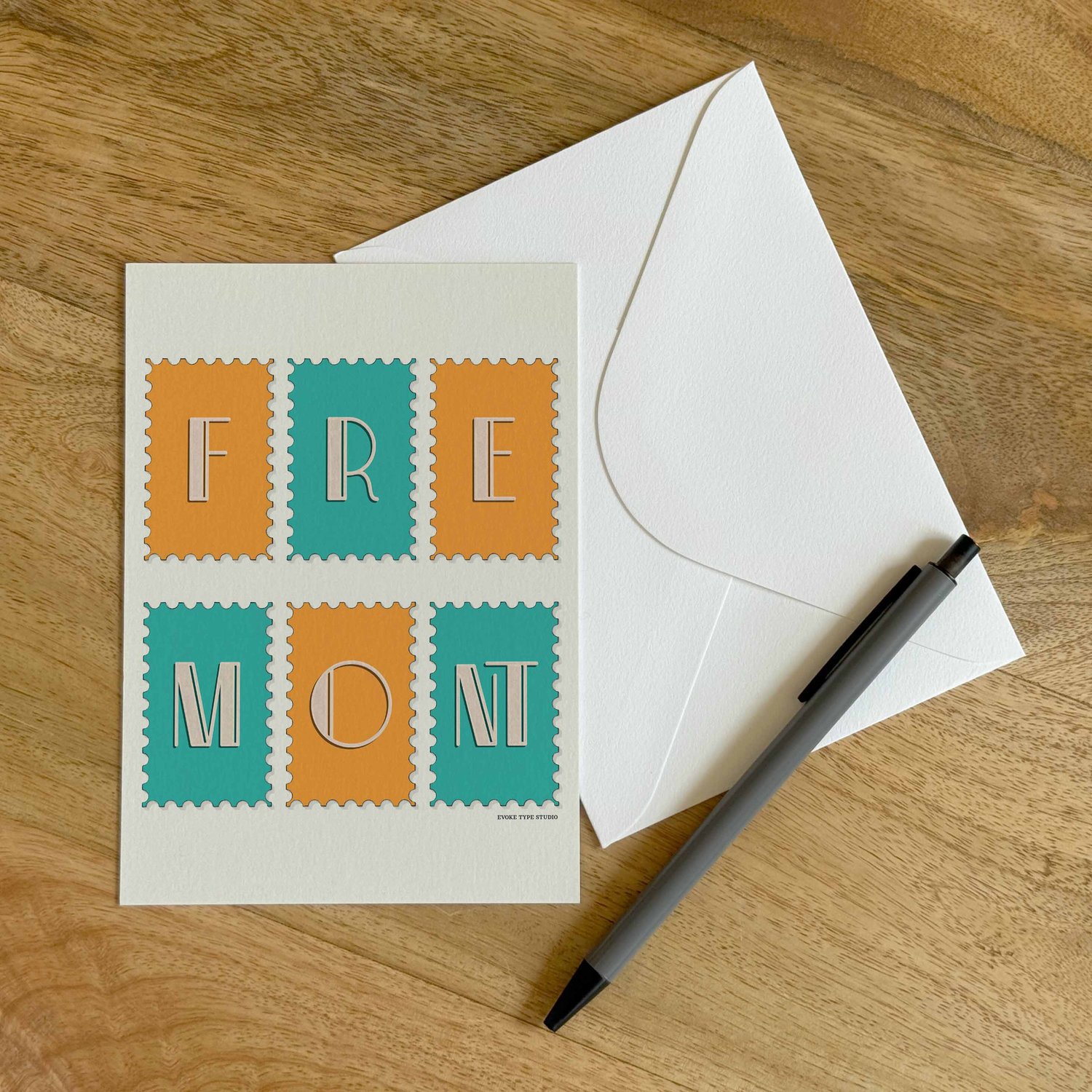 A colorful notecard sitting on a table with a white envelope and pen.