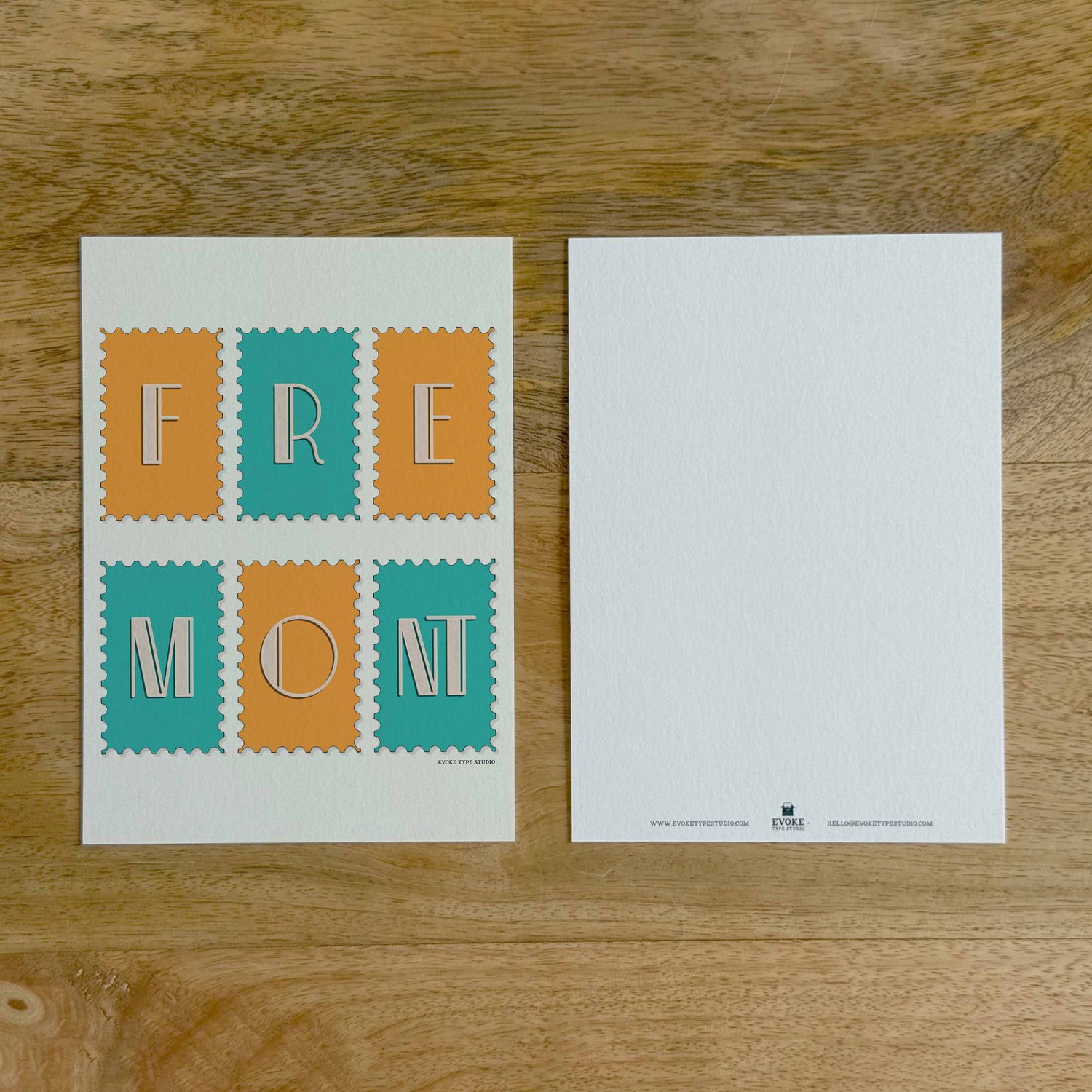 Two sides of a notecard, with postage stamp artwork on the front and a mostly blank back with company contact information at the bottom of the notecard.
