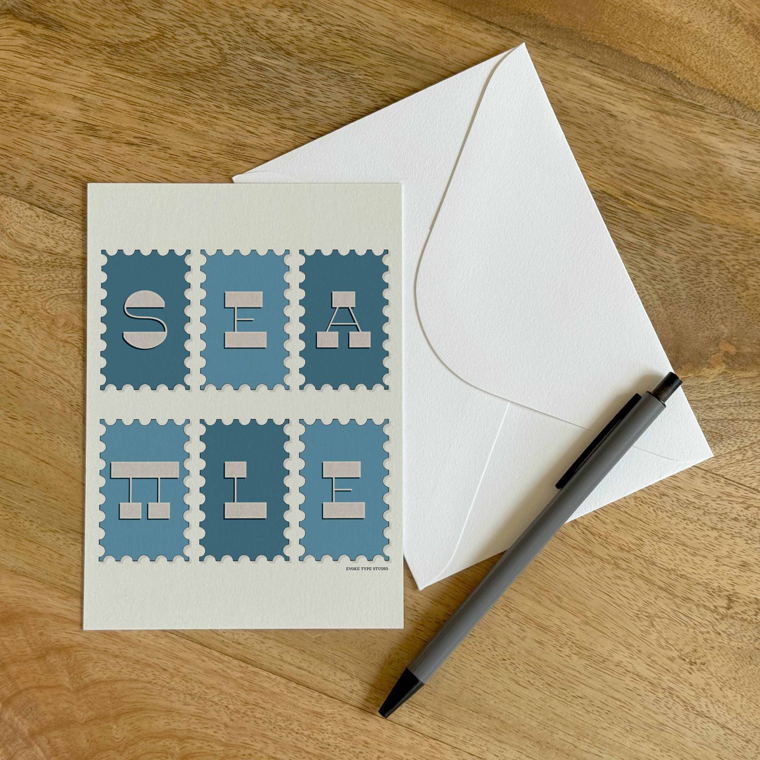 A colorful notecard sitting on a table with a white envelope and pen.