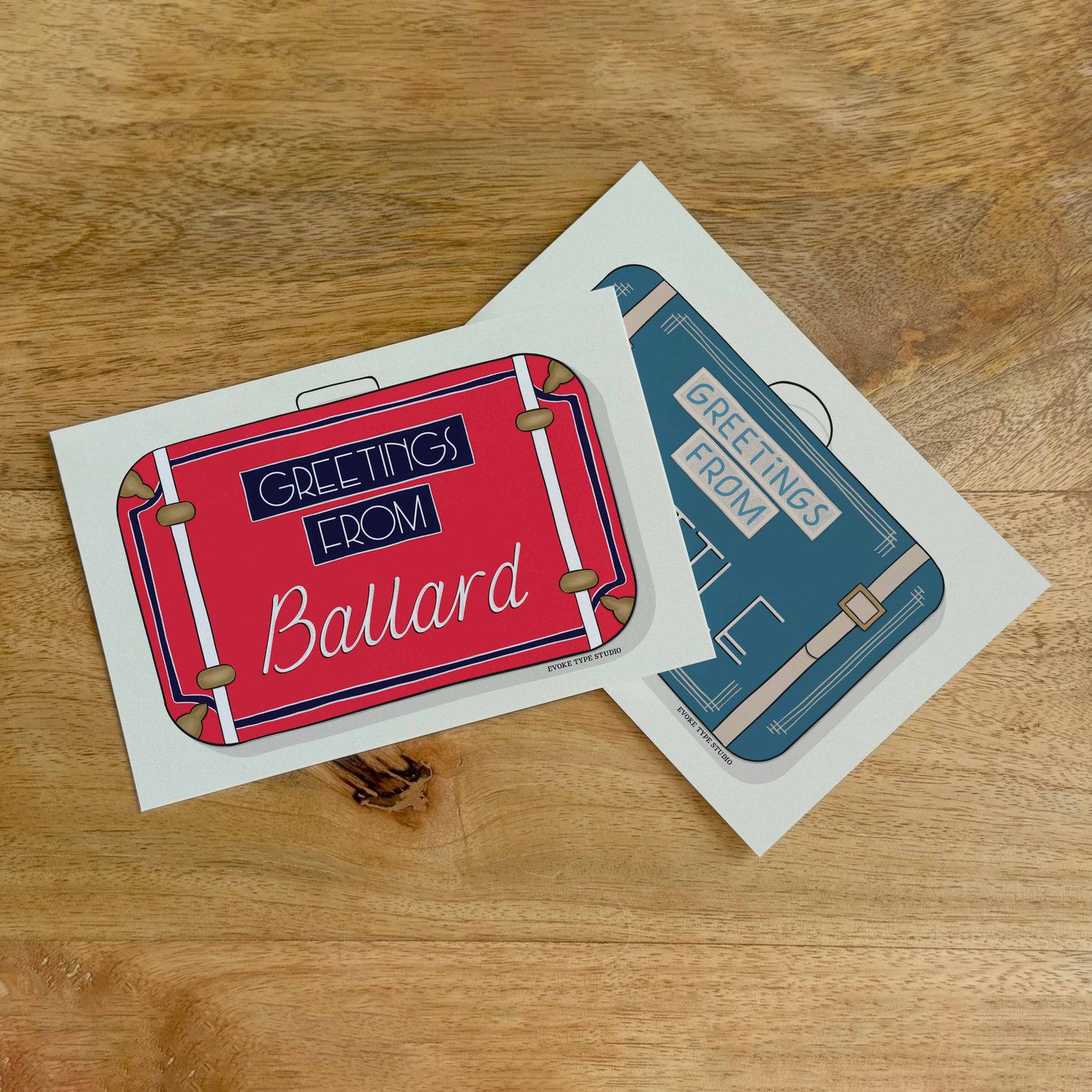 Two postcards, one placed on top of the other. Both postcards feature vintage suitcase illustrations and are for the Seattle, Washington area.