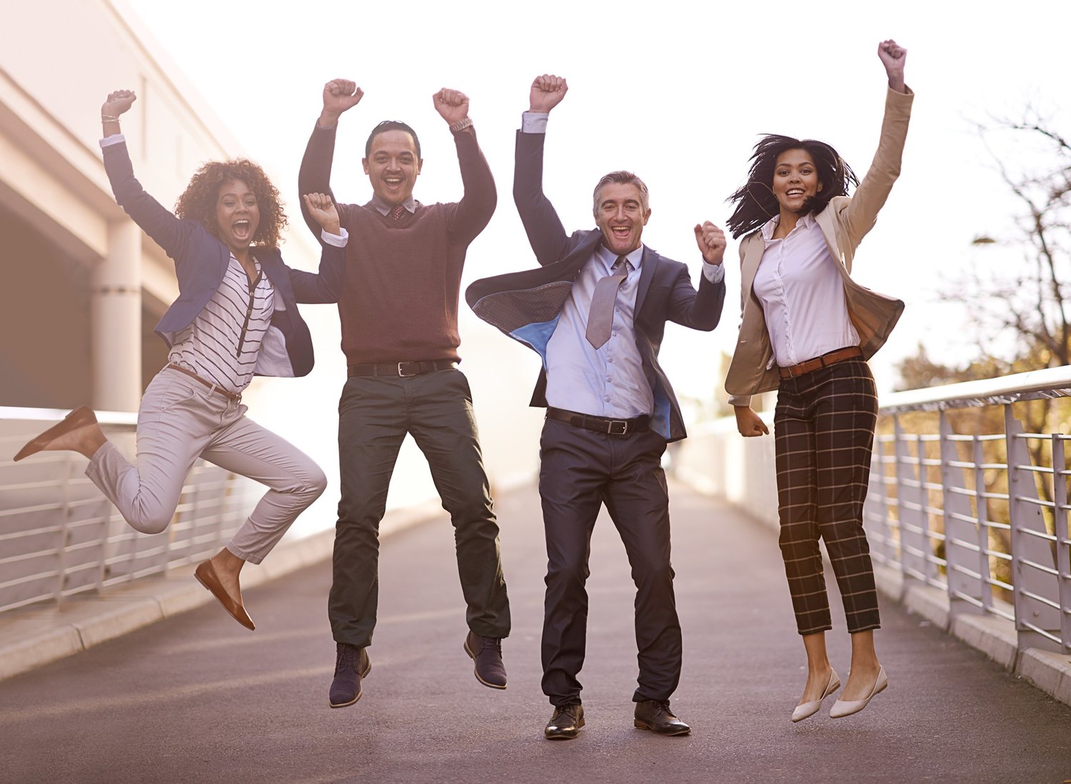 Diverse group of professionals jumping and celebrating outdoors, symbolizing confidence from thinking in English without translating