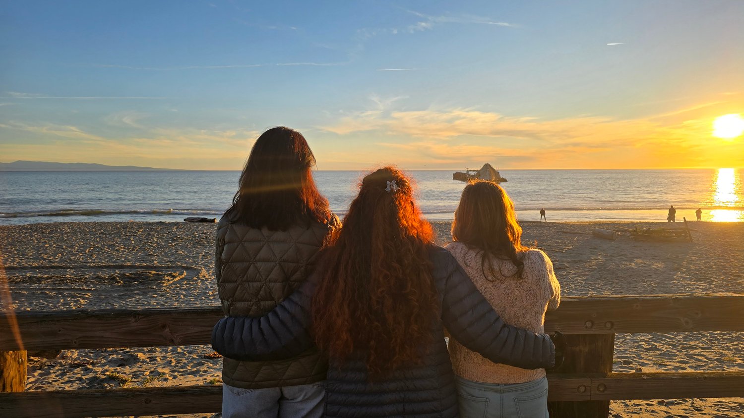 photograph of three women friends arm in arm watching the sunset - celebrating connection and friendship