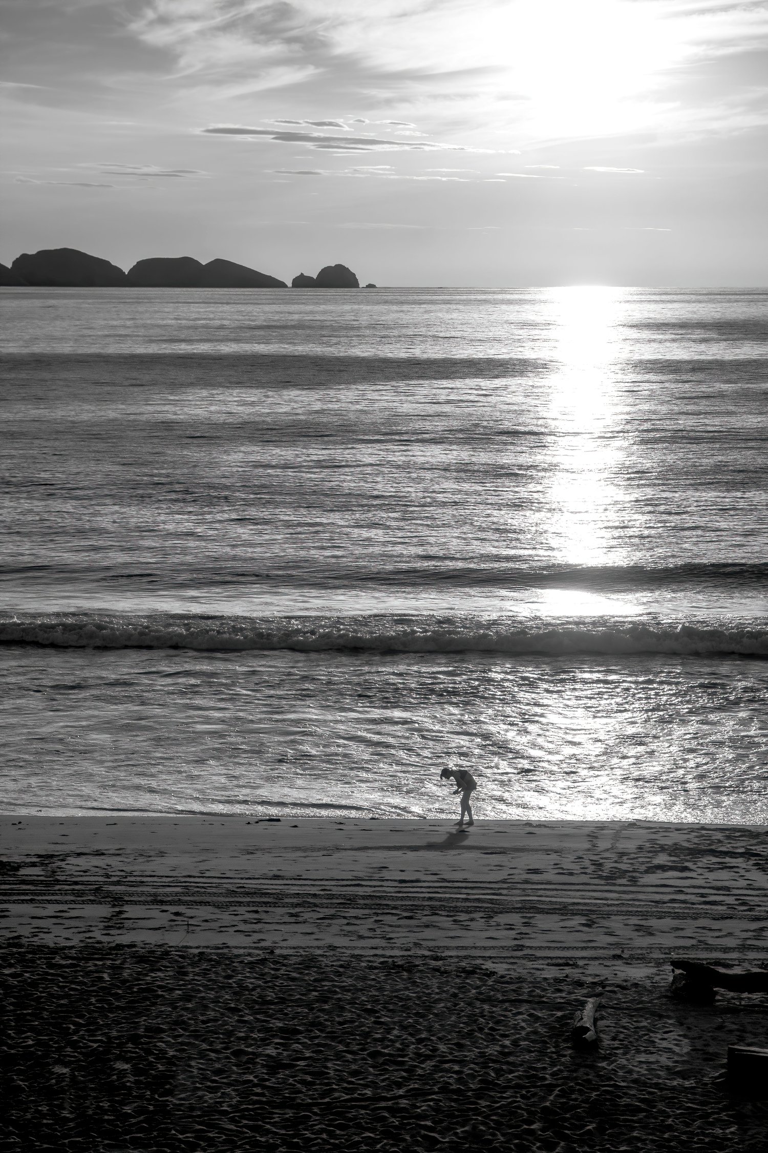 black and white sunset, lone figure beach photo, moody seascape print, silhouette at sunset, dramatic coastal art, fine art black and white, storytelling beach photo, contemplative ocean scene, monochrome wall art, minimalist beach silhouette