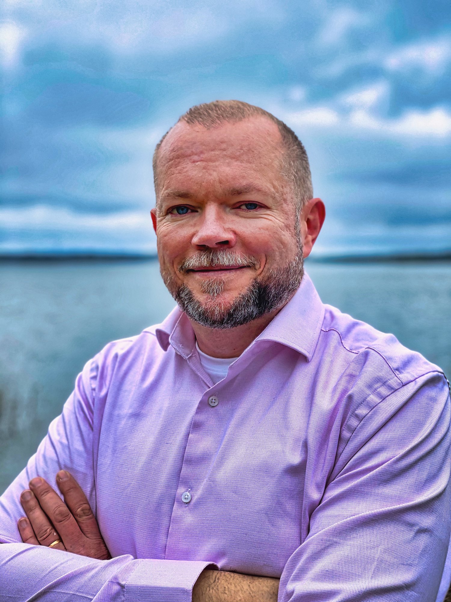 Per Axbom smiling, with arms crossed in front of a body of water