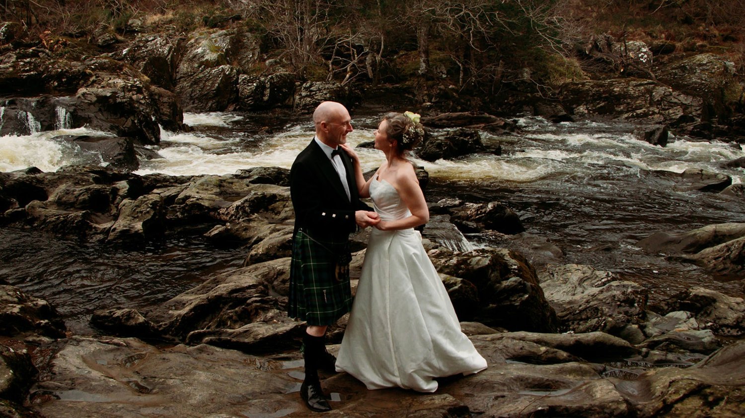 Standing together on a river bank on our Highland elopement