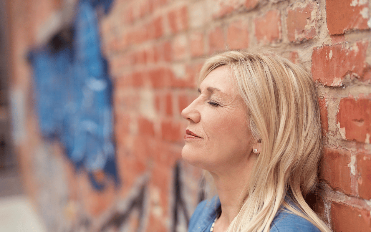 Midlife woman noticing small joys. “Mindful practices to reconnect with happiness. ” Anhedonia midlife. emotional burnout, nervous system reset, reconnect with joy, hypnotherapy for midlife wellbeing, midlife mental health.