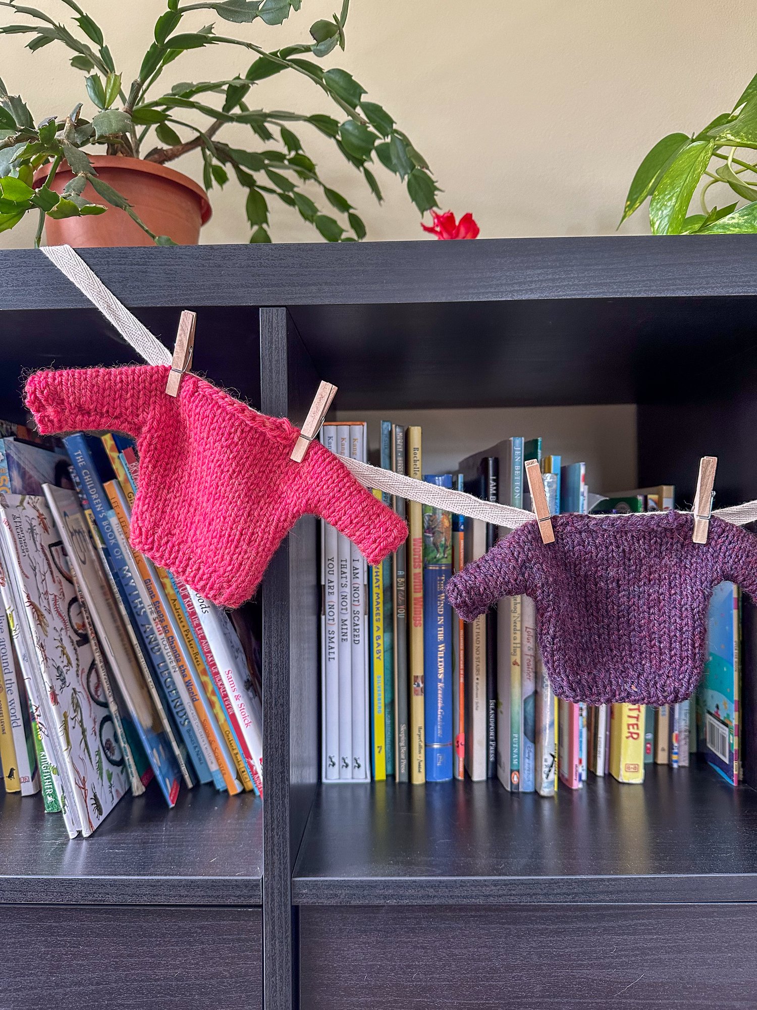 Close up of two mini sweaters: one pink and one purple
