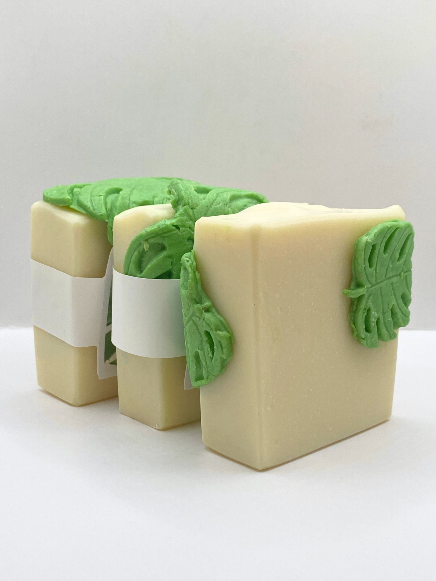 Handmade white soap draped with a green soap monstera leaf