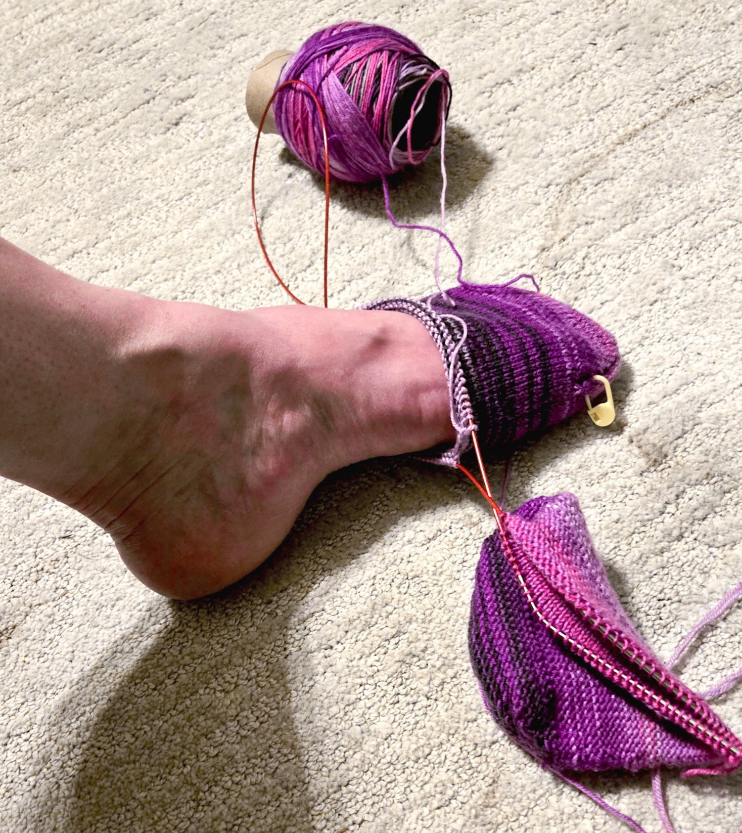 a partially knitted purple sock being tried on toe up to the ball of the foot