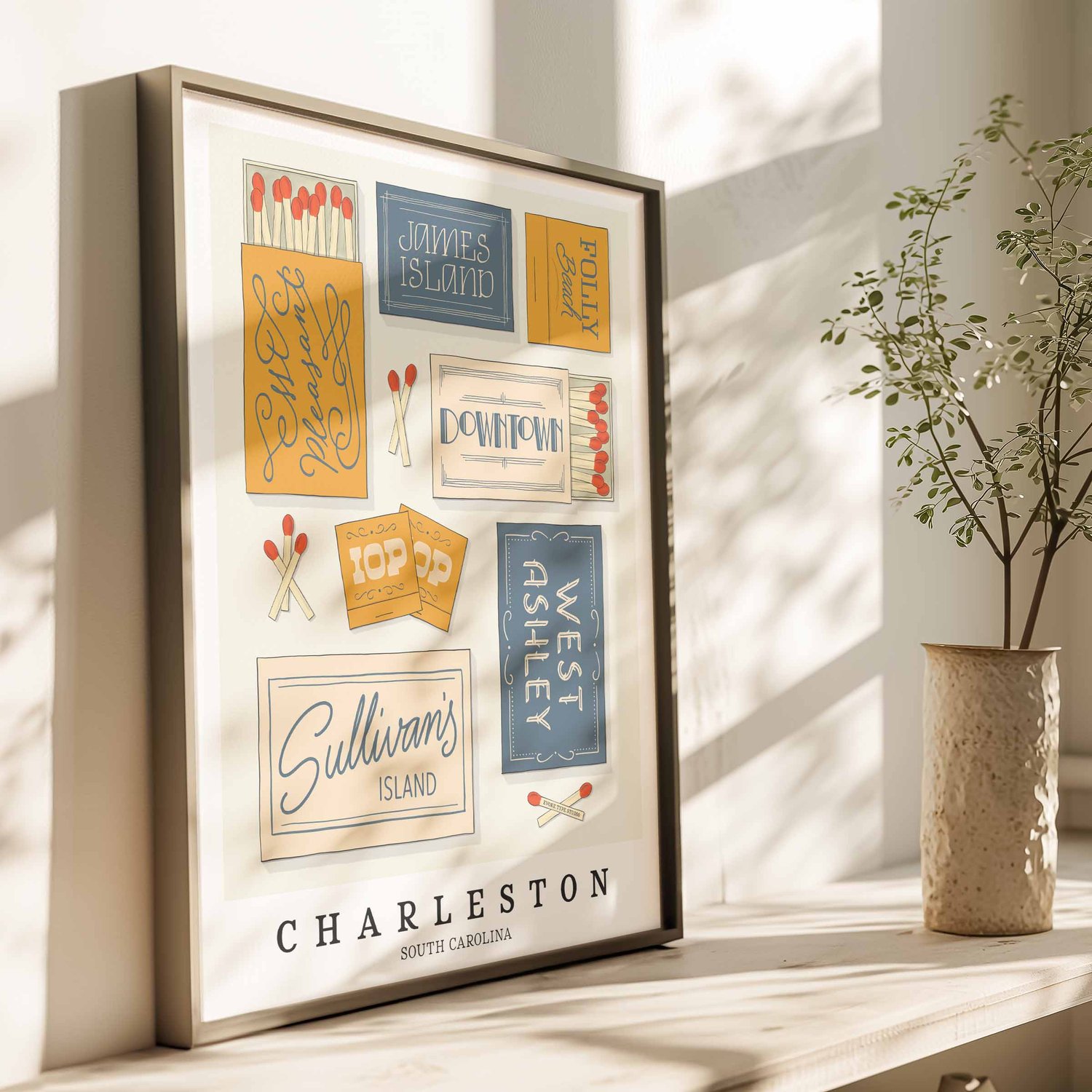 A framed picture of Charleston, South Carolina neighborhoods drawn in various lettering styles on matchboxes. Artwork has a blue, yellow and beige color scheme.