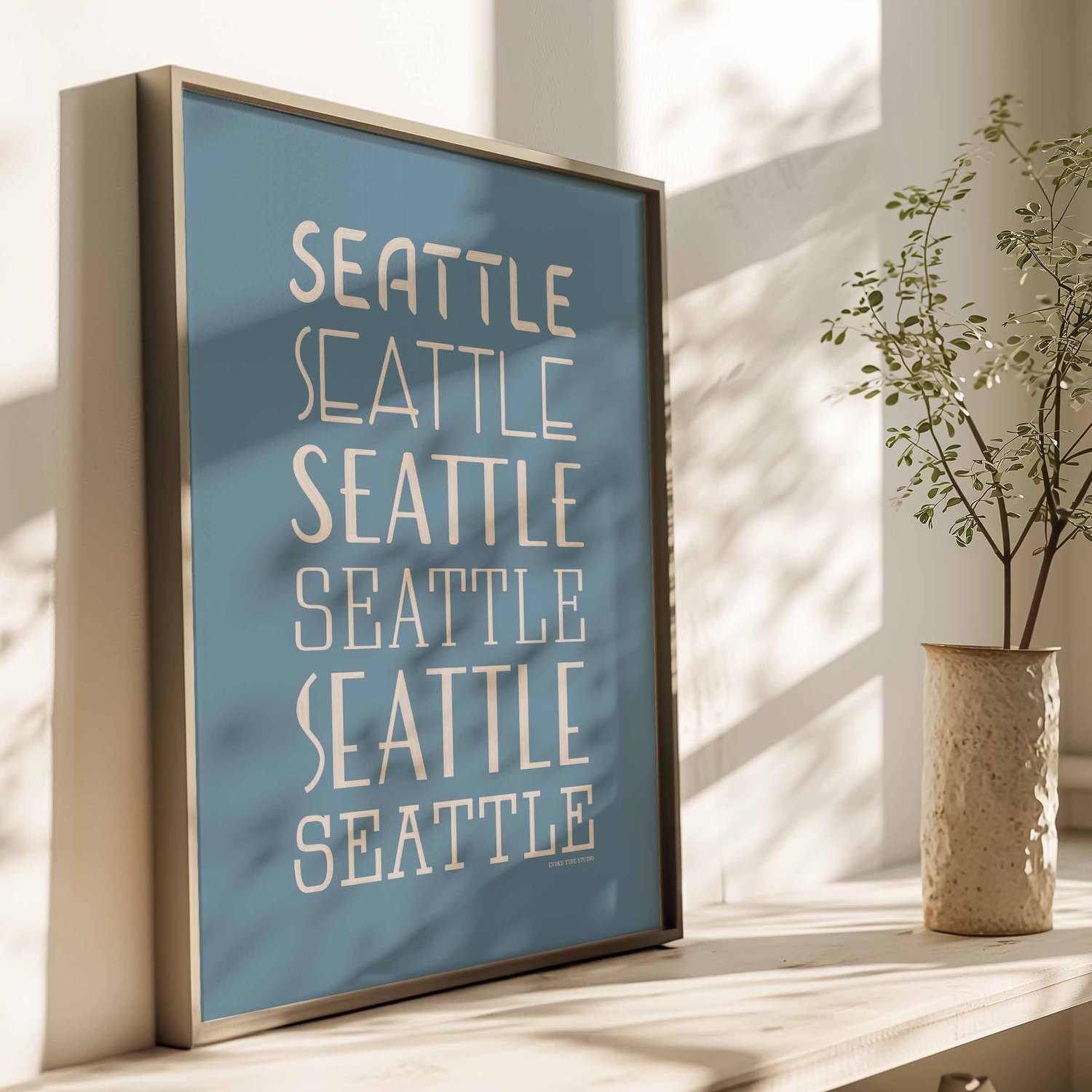 A framed picture of the word "Seattle" drawn in various lettering styles. Artwork has a blue and beige color scheme