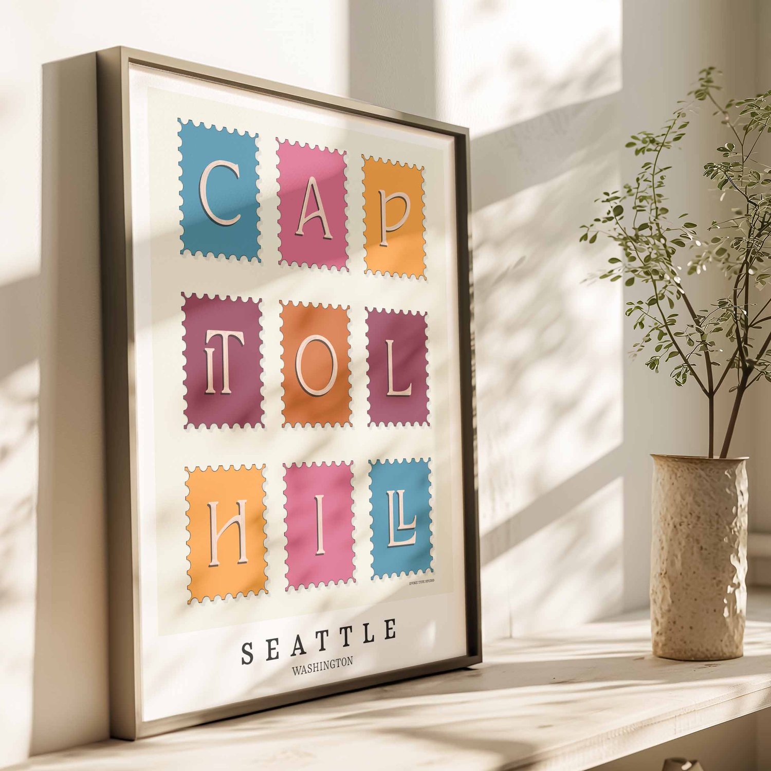 A framed picture of postage stamps featuring the Capitol Hill neighborhood in Seattle, Washington drawn in a unique lettering style. Artwork has a bright blue, orange and purple color scheme