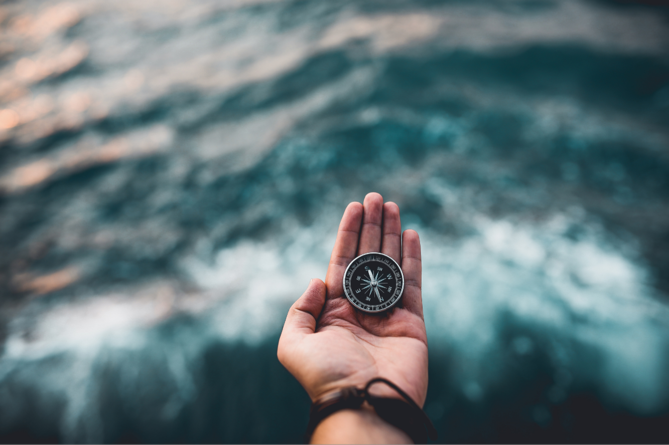 Hand holding compass to help navigate grief after parent loss through self-guided workshop