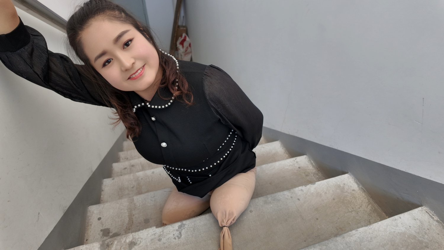 Tina, an amputee girl, uses a stool to go up and down the stairs.
