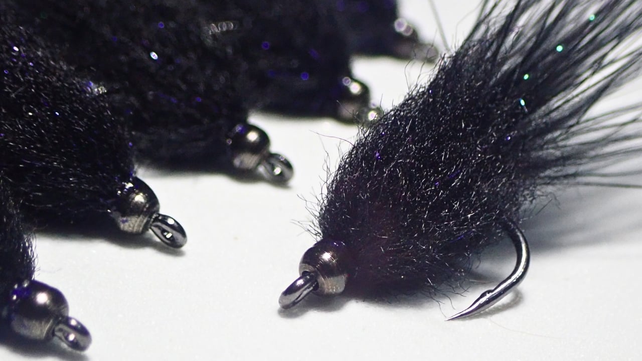 Close-up of six black Mini Leech streamer flies, hand-tied by Matt Campbell.