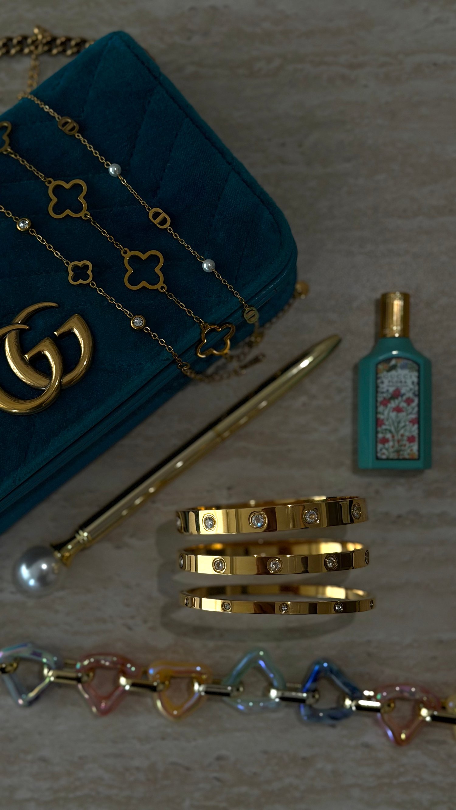 Stacked and chaine stainless steel bracelets worn on the wrist minimalist jewelry with a quiet luxury aesthetic with a old money luxury bag perfume and gold pearl pen by Le Maga bling