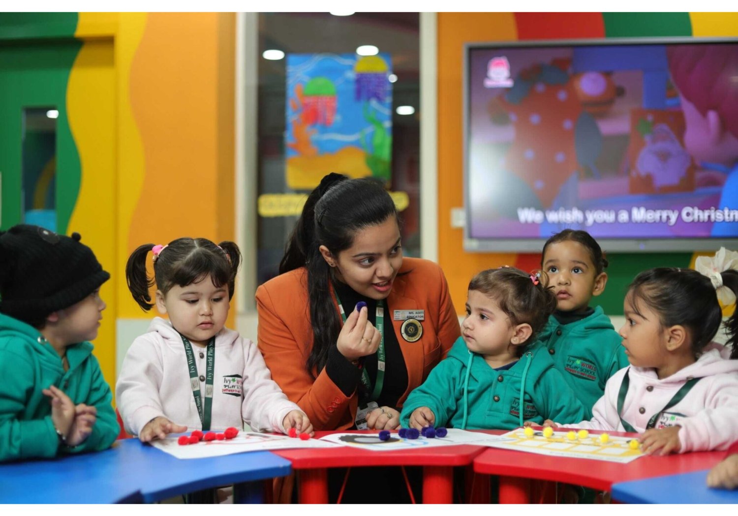 Teacher supporting early years children to develop secure foundations in literacy and numeracy, meeting Ofsted early years standards