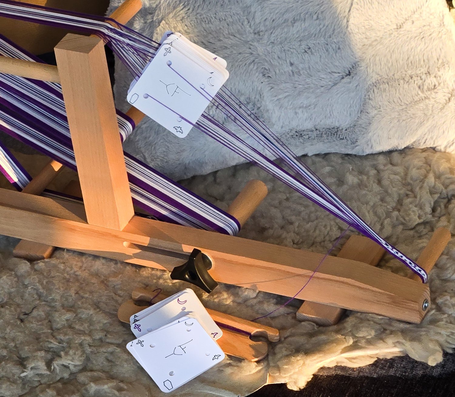 tablet weaving cards threaded on an inkle loom & a stack of extra cards next to the beater