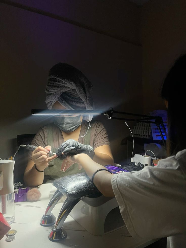 A nail technician carefully creating colorful nail art on a client’s nails in a bright, organized studio.