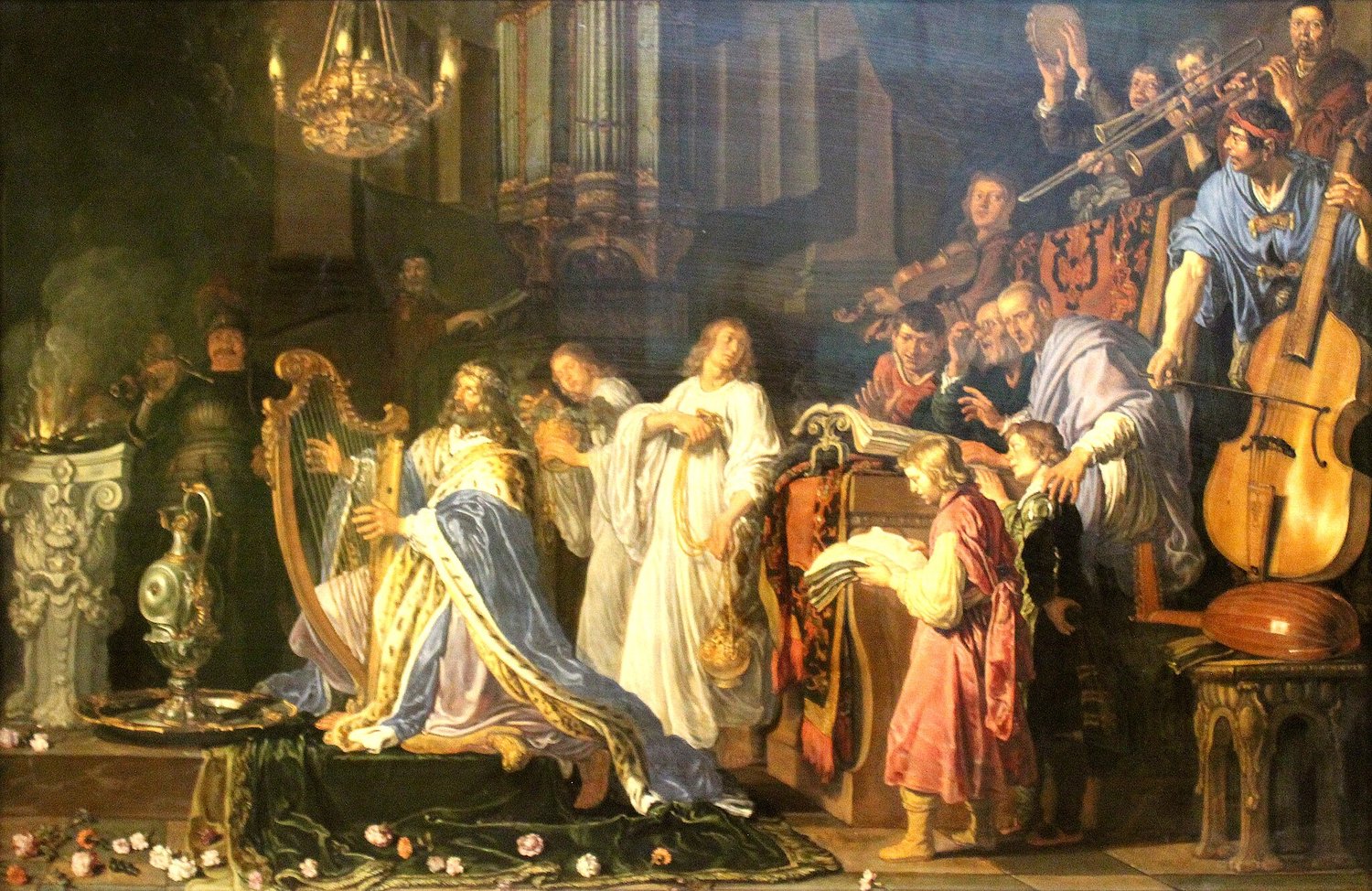 A 1618 painting of King David in a suspiciously church-like temple. He is wearing a blue ermine-lined cloak and playing an ornate gold lap harp. He is accompanied by singers and musicians. There is a bass viol on the right of the painting. Pieter Lastman,