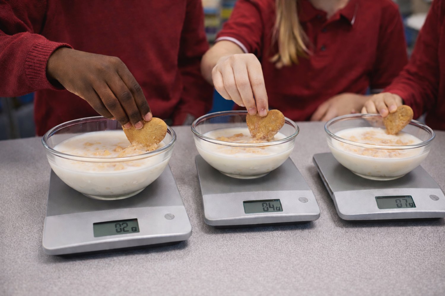 Heart-shaped biscuits being dunked in milk and weighed on kitchen scales