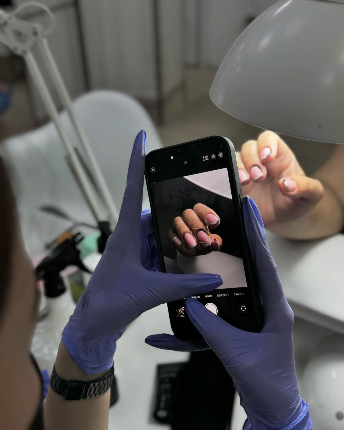 Nail technician applying detailed nail art on a client’s nails in a clean, modern nail studio, showcasing skill and precision.