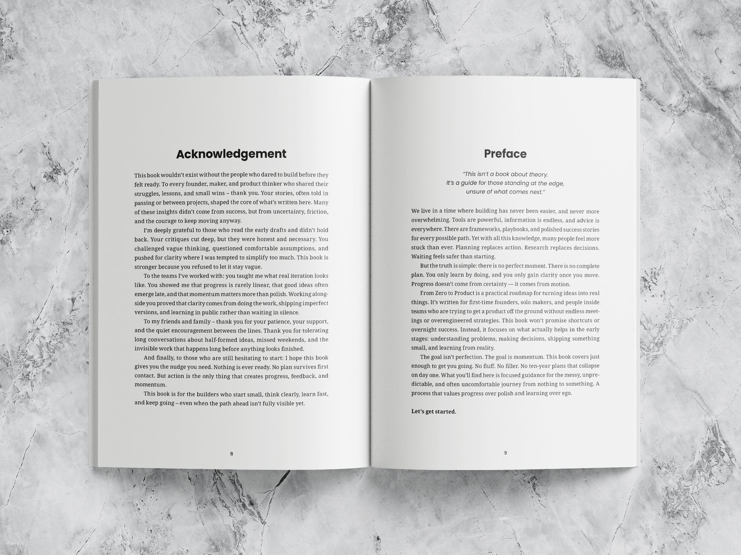 Open book with white pages and black text. The left page is titled “Acknowledgements” and the right page “Foreword.” The book lies open on a marble surface.
