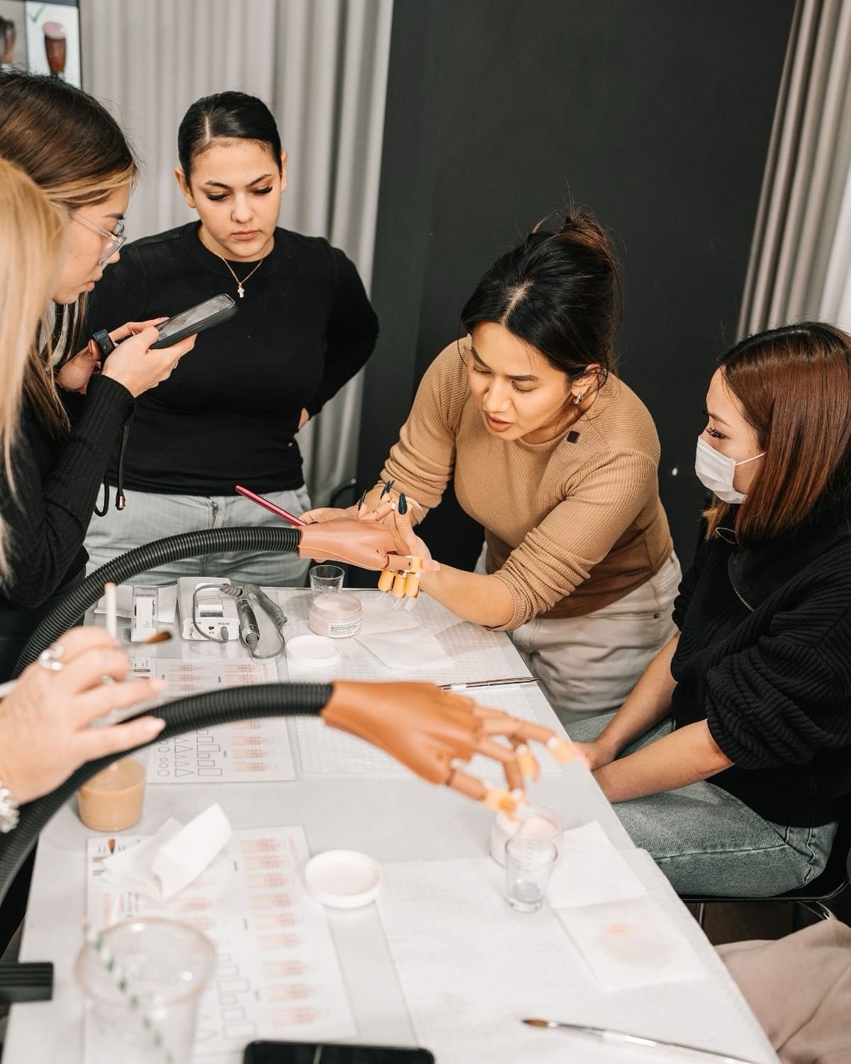 Professional nail technician painting detailed nail art on a client’s nails in a modern, organized nail studio, showcasing skill and precision.
