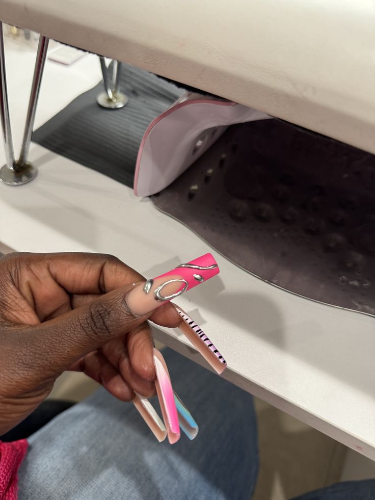 Professional nail technician applying detailed nail art on a client’s nails in a clean, modern nail studio, demonstrating skill and precision