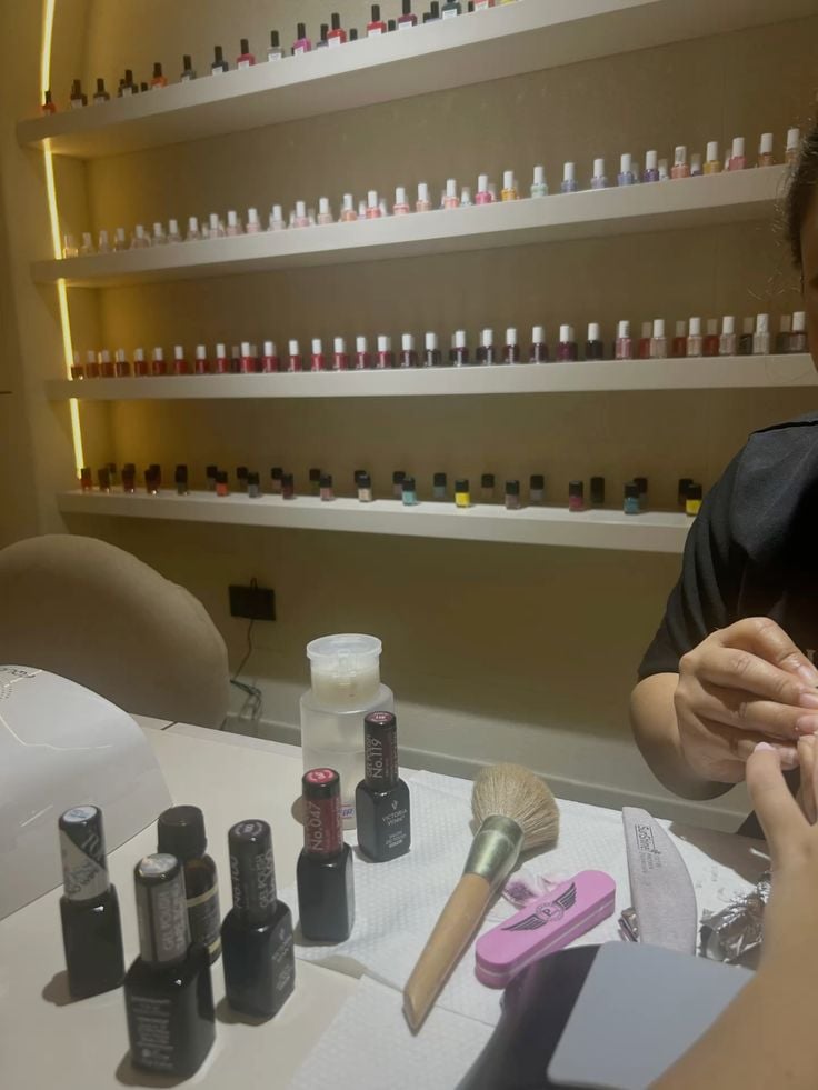 A nail technician carefully creating intricate nail designs on a client’s nails in a bright, modern studio.