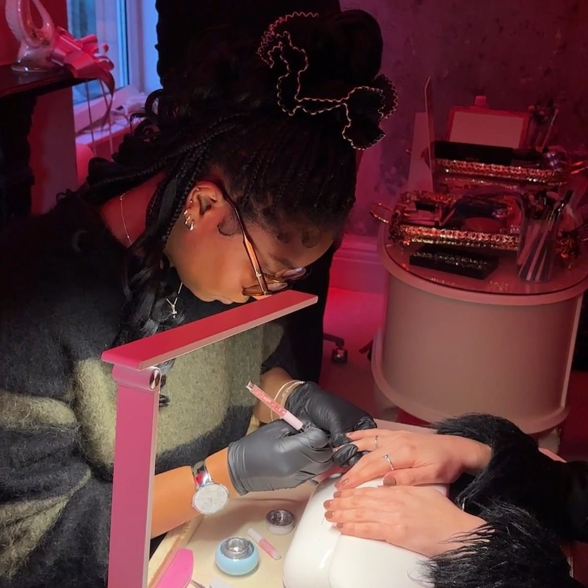 Nail technician carefully applying intricate nail art on a client’s nails in a clean, modern nail studio, showing professional skill and precision.