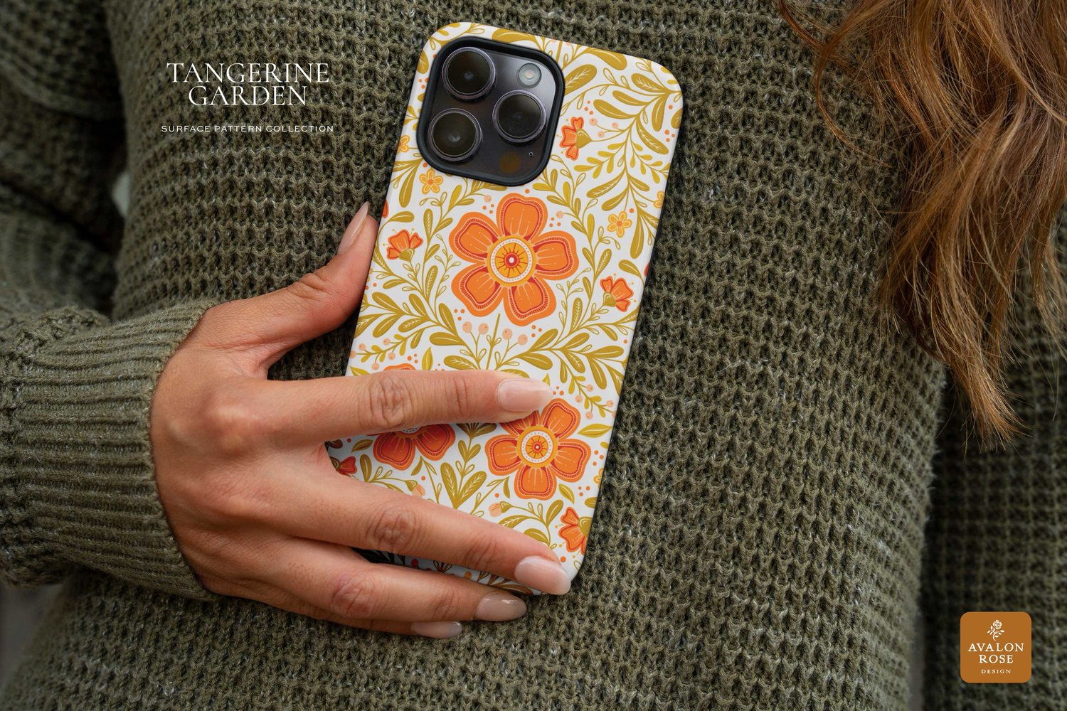 a woman in a green sweater holding a cellphone with a floral case