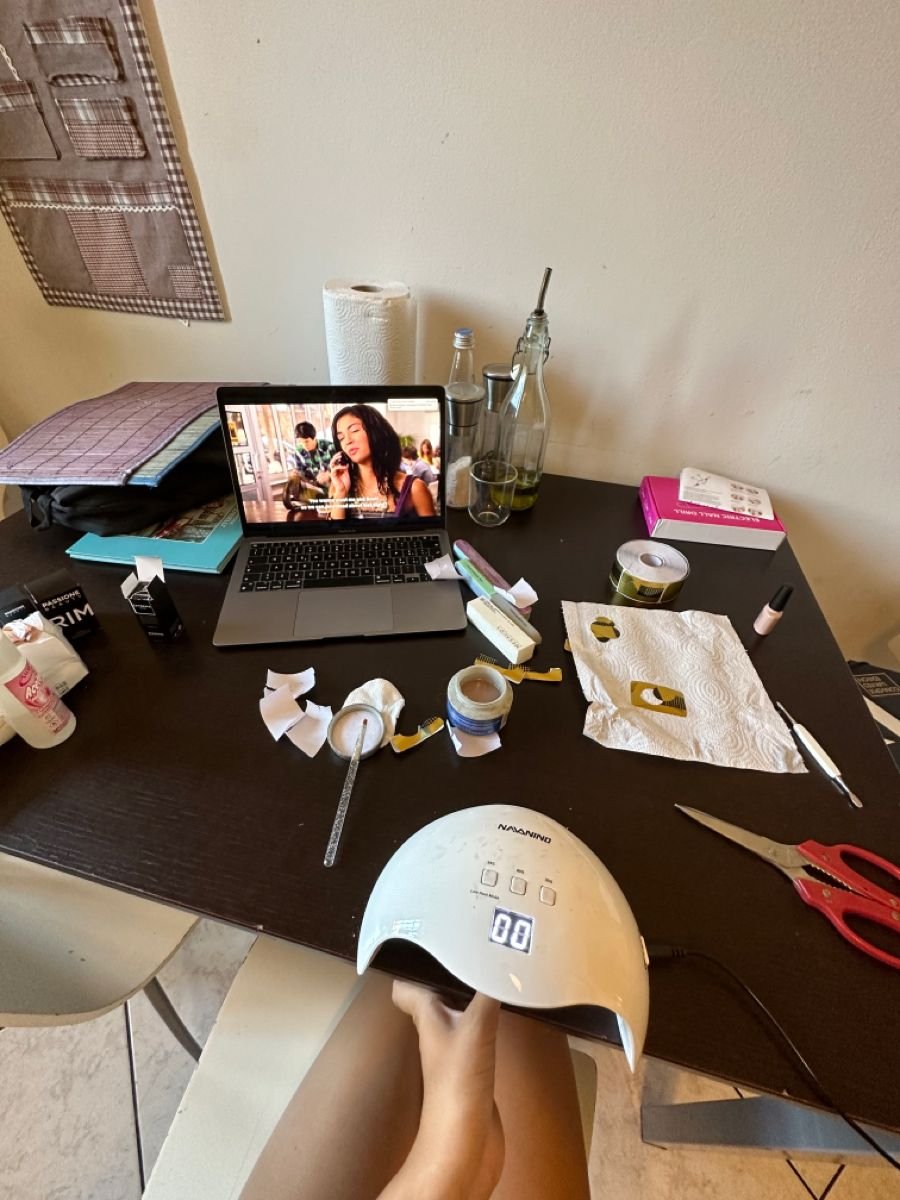 Nail technician planning nail designs and reviewing tools at a clean workspace, focusing on business growth and skill development.