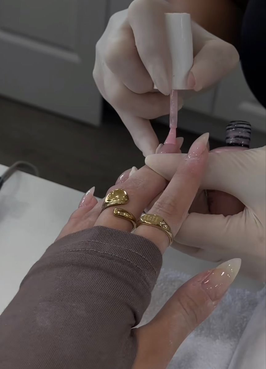 ail technician painting intricate nail art on a client’s hands in a clean, well-lit nail studio, demonstrating focus, precision, and professional skill.