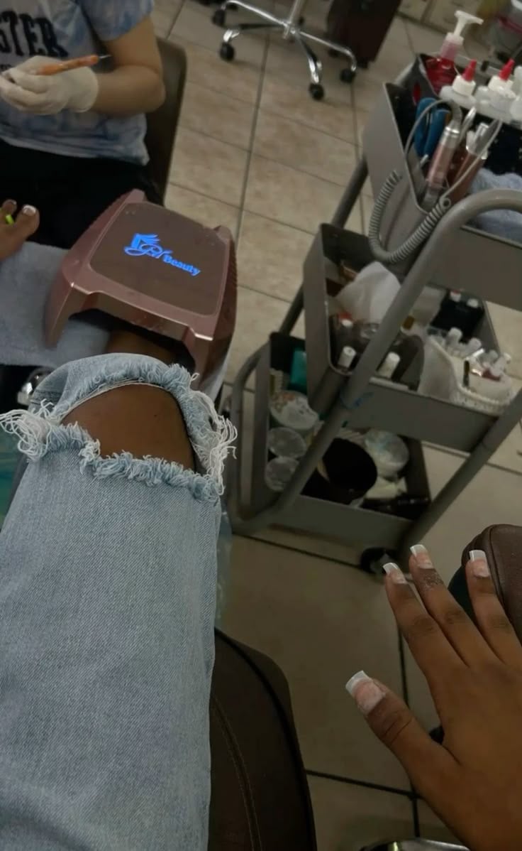 Nail technician applying nail polish in a bright, organized nail studio, demonstrating focus, precision, and consistency.