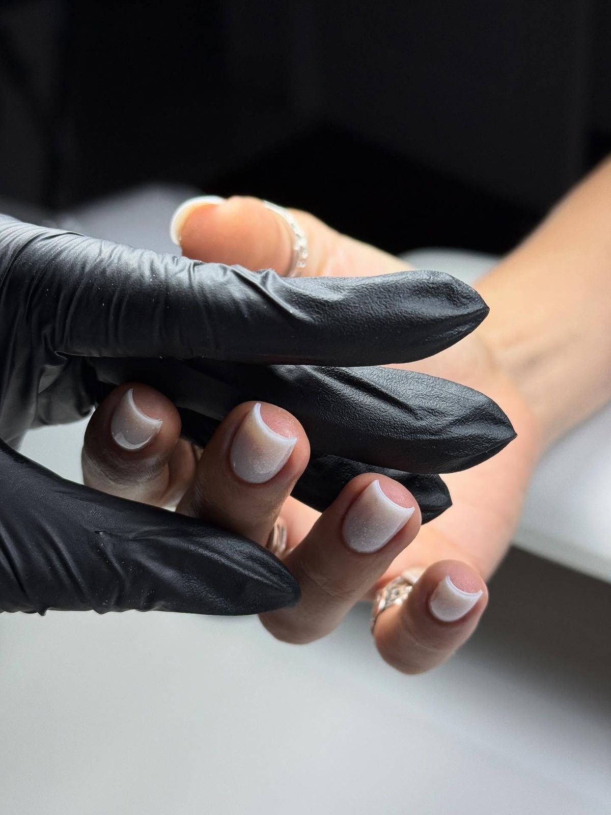 Nail technician carefully painting intricate nail designs on a client’s nails in a modern, organized studio, demonstrating precision, focus, and professional skill.