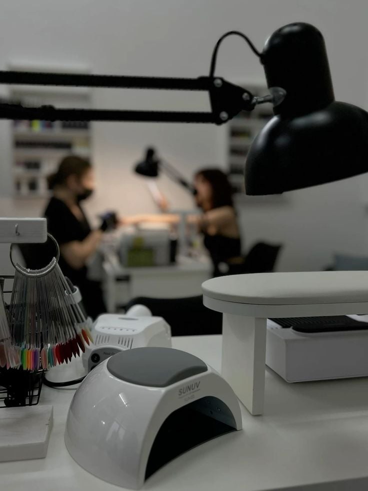 Nail technician welcoming a client in a bright, organized nail studio, showcasing professional client service and friendly interaction.